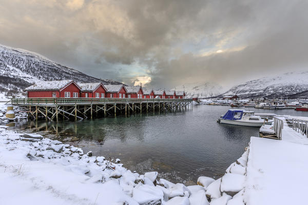 Typical red wooden huts of fishermen in the snowy and icy landscape of Lyngen Alps Tromsø Lapland Norway Europe