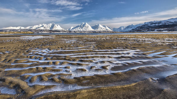 The icy sandy beach surrounding the snow capped mountains Breivikeidet Lyngen Alps Tromsø Lapland Norway Europe