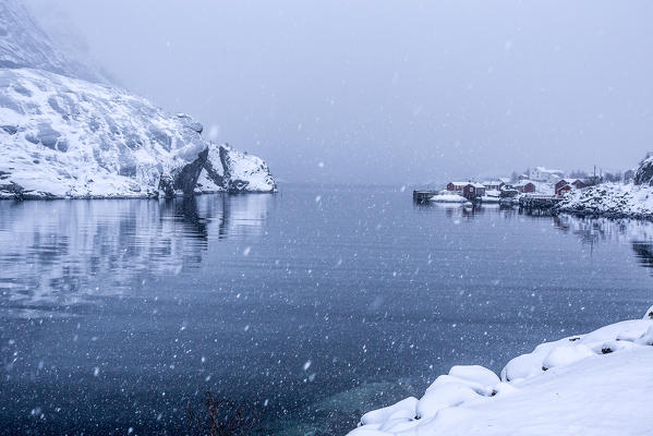 Heavy snowfall on the fishing village and the icy sea Nusfjord Lofoten Islands Norway Europe