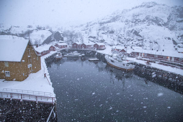 Heavy snowfall on the fishing village and the icy sea Nusfjord Lofoten Islands Norway Europe