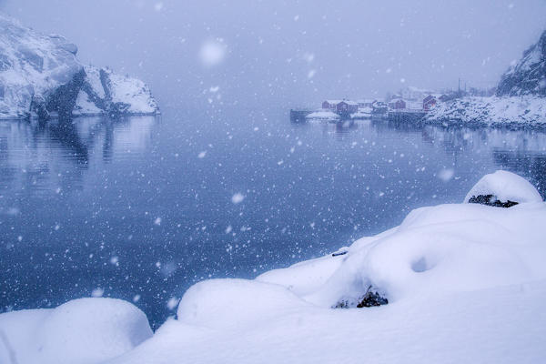 Heavy snowfall on the fishing village and the icy sea Nusfjord Lofoten Islands Norway Europe