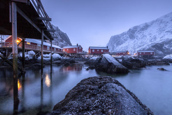 Typical fishermen houses called rorbu in the  snowy landscape at dusk Nusfjord Nordland County Lofoten Islands Norway Europe