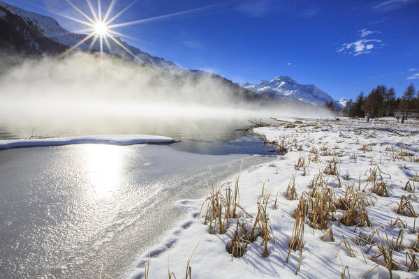 Winter sun light up the frozen Lake Silvaplana surrounded by mist Maloja Canton of Graubünden Engadine Switzerland Europe