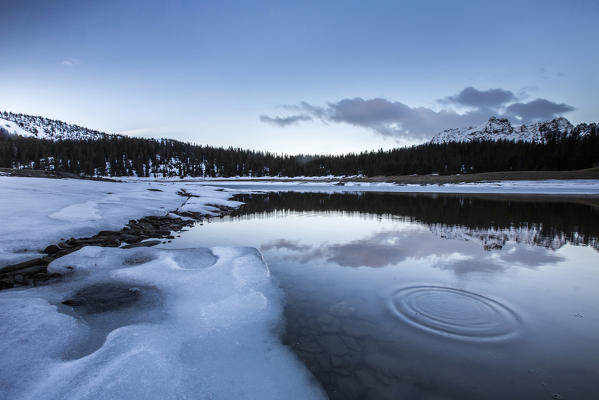 Spring thaw and woods reflected at dusk in Lake Palù Province of Sondrio Malenco Valley Valtellina Lombardy Italy Europe