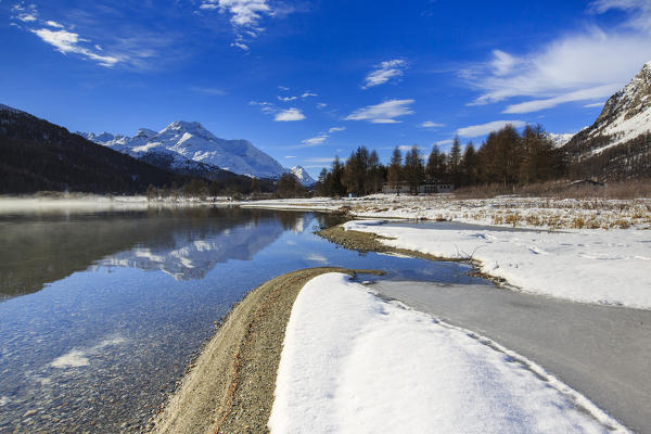 Snowy peaks are reflected in Lake Silvaplana still partially frozen Maloja Canton of Graubünden Engadine Switzerland Europe