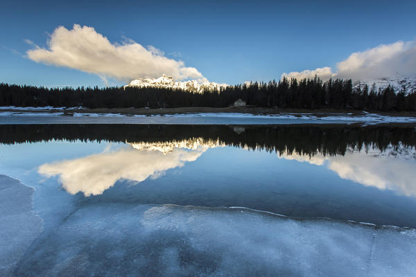 The spring thaw melts ice while snowy peaks are reflected in Lake Palù Sondrio Malenco Valley Valtellina Lombardy Italy Europe