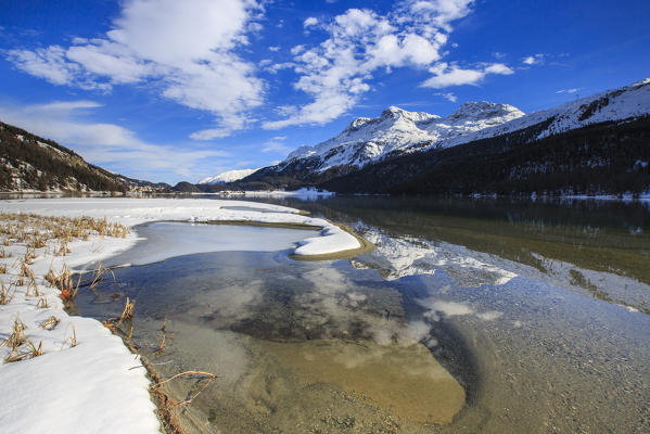 Snowy peaks are reflected in Lake Silvaplana still partially frozen Maloja Canton of Graubünden Engadine Switzerland Europe