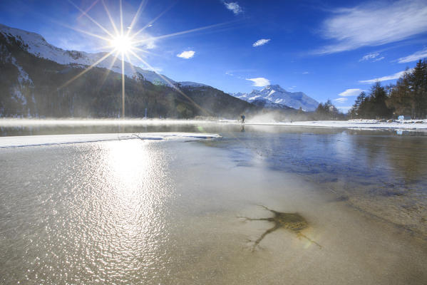 Winter sun light up the frozen Lake Silvaplana surrounded by mist Maloja Canton of Graubünden Engadine Switzerland Europe