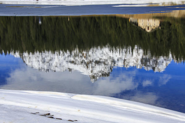 The spring thaw melts ice while snowy peaks are reflected in Lake Palù Sondrio Malenco Valley Valtellina Lombardy Italy Europe