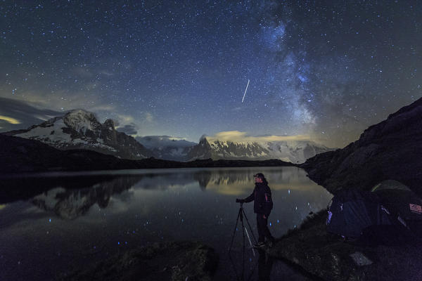 Photographer under starry sky and Milky Way reflected on Lac de Cheserys Chamonix Haute Savoie France Europe