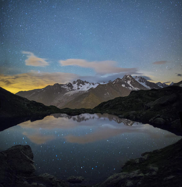 The stars illuminate the snowy peaks and reflected in Lac de Cheserys Chamonix Haute Savoie France Europe