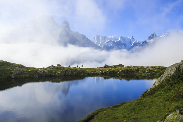 Low clouds and mist around Grandes Jorasses  while hikers proceed on Lac De Cheserys Haute Savoie France Europe