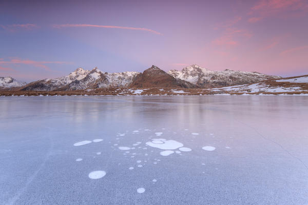 Ice bubbles on the frozen surface of Andossi Lake at sunrise Spluga Valley Valtellina Lombardy Italy Europe