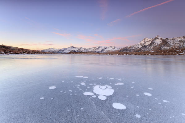 Ice bubbles on the frozen surface of Andossi Lake at sunrise Spluga Valley Valtellina Lombardy Italy Europe