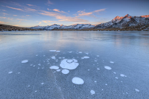 Ice bubbles on the frozen surface of Andossi Lake at sunrise Spluga Valley Valtellina Lombardy Italy Europe