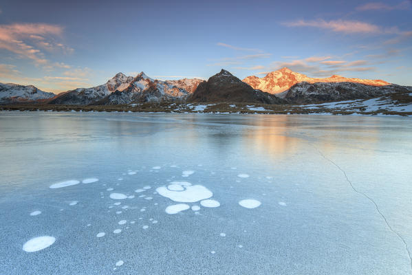 Ice bubbles on the frozen surface of Andossi Lake at sunrise Spluga Valley Valtellina Lombardy Italy Europe