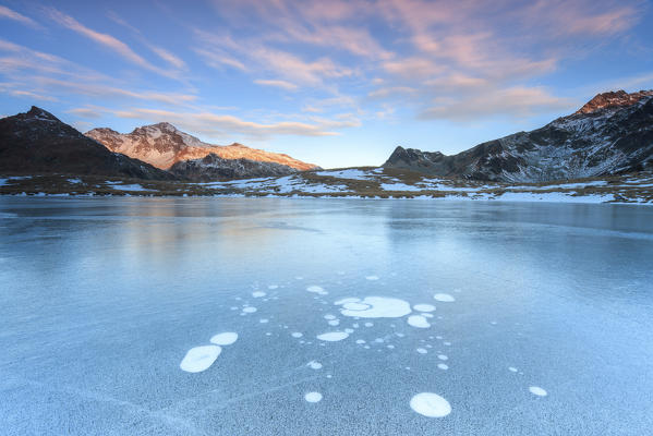 Ice bubbles on the frozen surface of the Andossi Lake at sunrise Spluga Valley Valtellina Lombardy Italy Europe