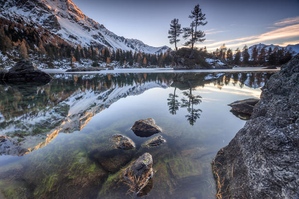 Autumn reflections at Saoseo Lake still partially frozen Poschiavo Valley Canton of Graubuenden Switzerland Europe