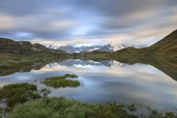 The snowy peaks are reflected in Fenetre Lakes at dawn Ferret Valley Saint Rhémy Grand St Bernard Aosta Valley Italy Europe