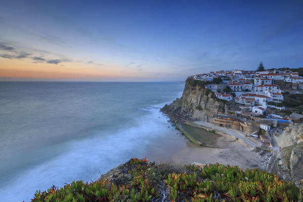 The soft colors of twilight frame the ocean and the village of Azenhas do Mar Sintra Portugal Europe