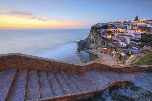 The soft colors of twilight frame the ocean and the village of Azenhas do Mar Sintra Portugal Europe