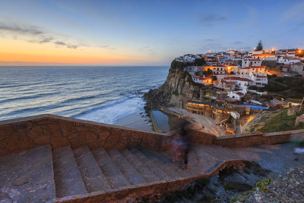 The soft colors of twilight frame the ocean and the village of Azenhas do Mar Sintra Portugal Europe
