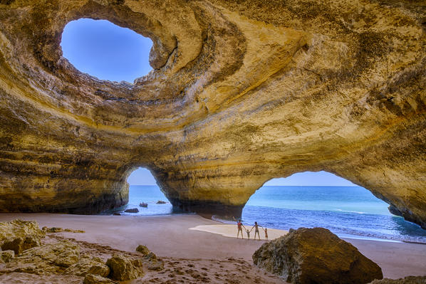 A family of tourist inside the sea caves of Benagil admire the blue waters of the ocean Faro District Algarve Portugal Europe