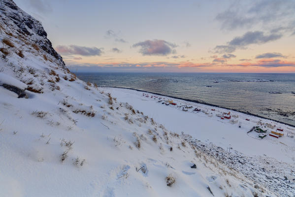 View of a fishing village surrounded by snow and cold sea under a pink sky Eggum Vestvagøy Island Lofoten Islands Norway Europe