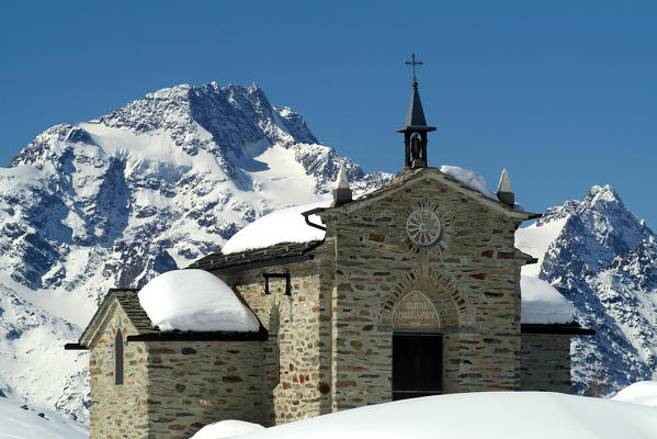 Mount Disgrazia stands behind the church Alpe Prabello in winter. Valmalenco. Valtellina. Lombardy. Italy Europe