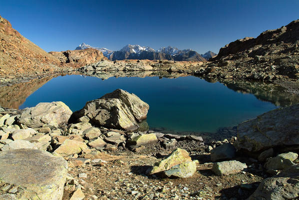 Still water in Lake Sassersa from which the view extends to the Group Scalino Painale and the peak of Ron. Valtellina. Italy Europe