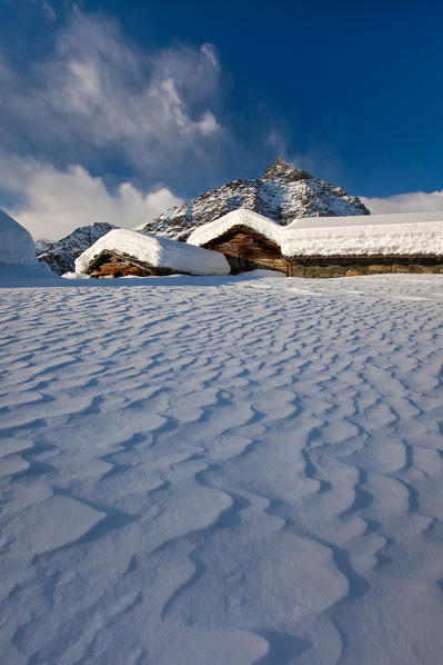 The wind shapes the snow that fell between the traditional huts of the Alpe Prabello. Valmalenco. Valtellina Lombardy. Italy Europe