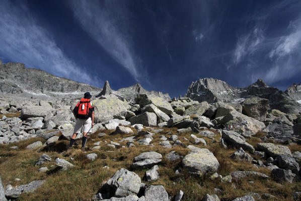 Hikers looking Pizzo Badile from the slope of the Val Porcellizzo during a sunny day. Valmasino. Valtellina. Lombardy Italy Europe