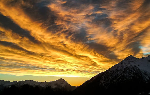 Colorful winter sunset on Lower Valtellina seen from the Alpe Granda. In the background the profile of the Alps orobie and Mount Legnone. Buglio in Monte Valtellina. Lombardy. Italy Europe