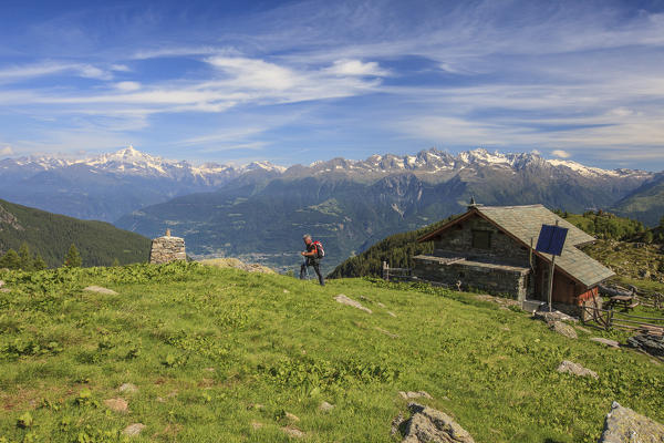 Hiker leaves the hut and proceeds in a summer sunny day Orobie Alps Arigna Valley Sondrio Valtellina Lombardy Italy Europe