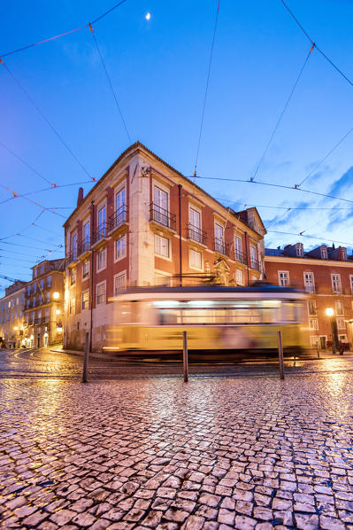 City lights on the typical architecture and  old streets at dusk while the tram 28 proceeds Alfama Lisbon Portugal Europe