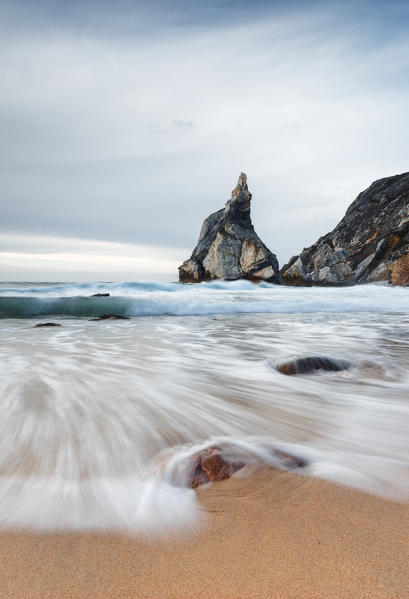 Ocean waves crashing on the sandy beach of Praia da Ursa surrounded by cliffs Cabo da Roca Colares Sintra Portugal Europe