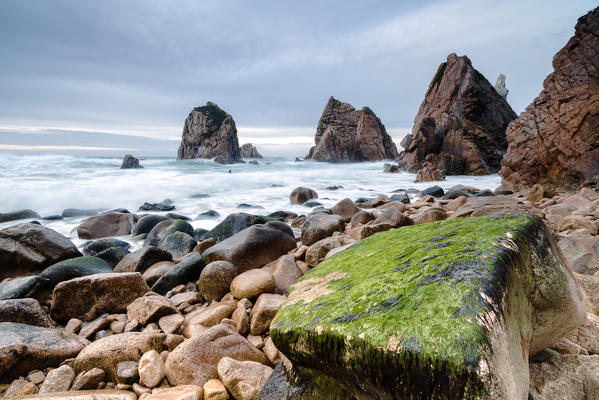 Ocean waves crashing on stones of Praia da Ursa beach surrounded by cliffs Cabo da Roca Colares Sintra Portugal Europe