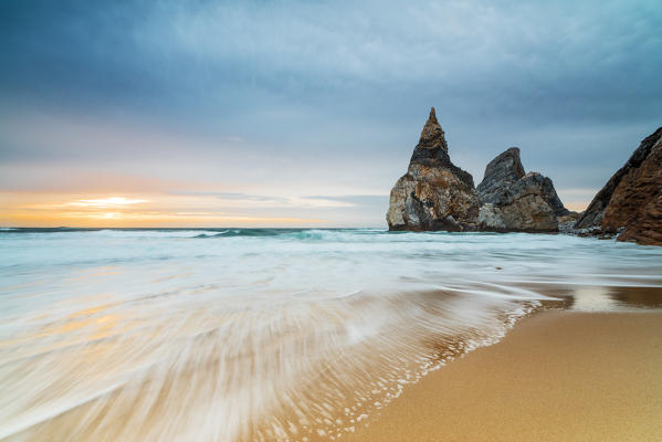 Ocean waves crashing on the beach of Praia da Ursa at sunset surrounded by cliffs Cabo da Roca Colares Sintra Portugal Europe