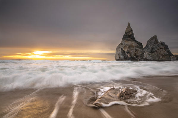 Ocean waves crashing on the beach of Praia da Ursa at sunset surrounded by cliffs Cabo da Roca Colares Sintra Portugal Europe