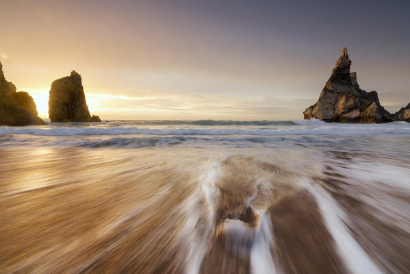 Ocean waves crashing on the beach of Praia da Ursa at sunset surrounded by cliffs Cabo da Roca Colares Sintra Portugal Europe