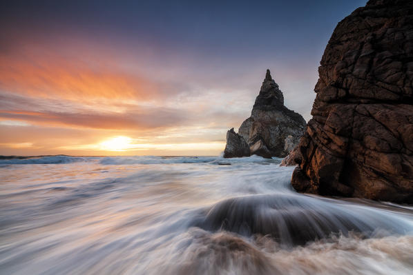 The fiery sky at sunset is reflected on the ocean waves and cliffs Praia da Ursa Cabo da Roca Colares Sintra Portugal Europe