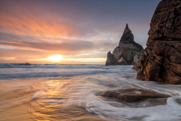 The fiery sky at sunset is reflected on the ocean waves and cliffs Praia da Ursa Cabo da Roca Colares Sintra Portugal Europe