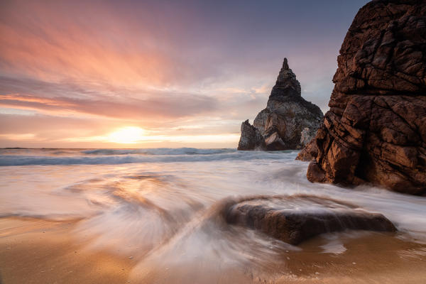 Golden reflections of the cliffs on Praia da Ursa beach bathed by ocean at sunset Cabo da Roca Colares Sintra Portugal Europe