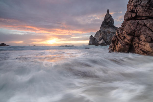 The fiery sky at sunset is reflected on the ocean waves and cliffs Praia da Ursa Cabo da Roca Colares Sintra Portugal Europe