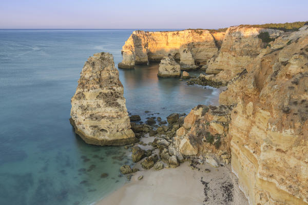 Sunrise on the cliffs and turquoise water of the ocean Praia da Marinha Caramujeira Lagoa Municipality Algarve Portugal Europe