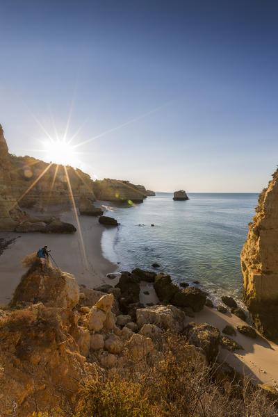 First rays of sun on the cliffs and turquoise water at Praia da Marinha Caramujeira Lagoa Municipality Algarve Portugal Europe