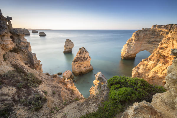 Sunrise on the cliffs and turquoise water of the ocean Praia da Marinha Caramujeira Lagoa Municipality Algarve Portugal Europe