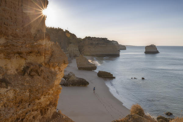 First rays of sun on the cliffs and turquoise water at Praia da Marinha Caramujeira Lagoa Municipality Algarve Portugal Europe