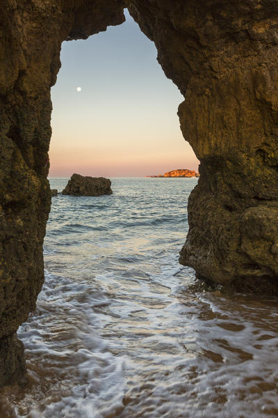A sea cave frames the ocean illuminated by the colors of dawn at Praia da Rocha Portimao Faro district Algarve Portugal Europe