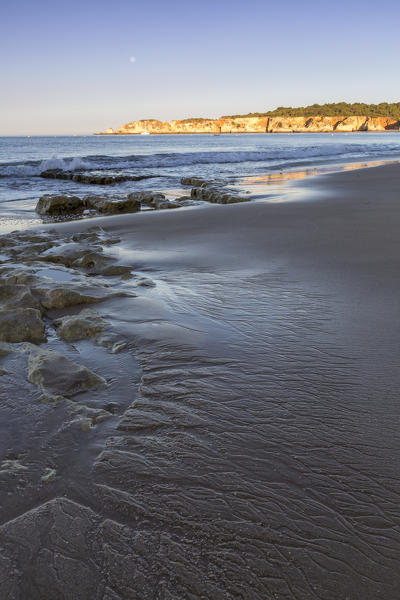 The newly risen sun shines on cliffs and reflected on the beach Praia da Rocha Portimao Algarve Faro District Portugal Europe